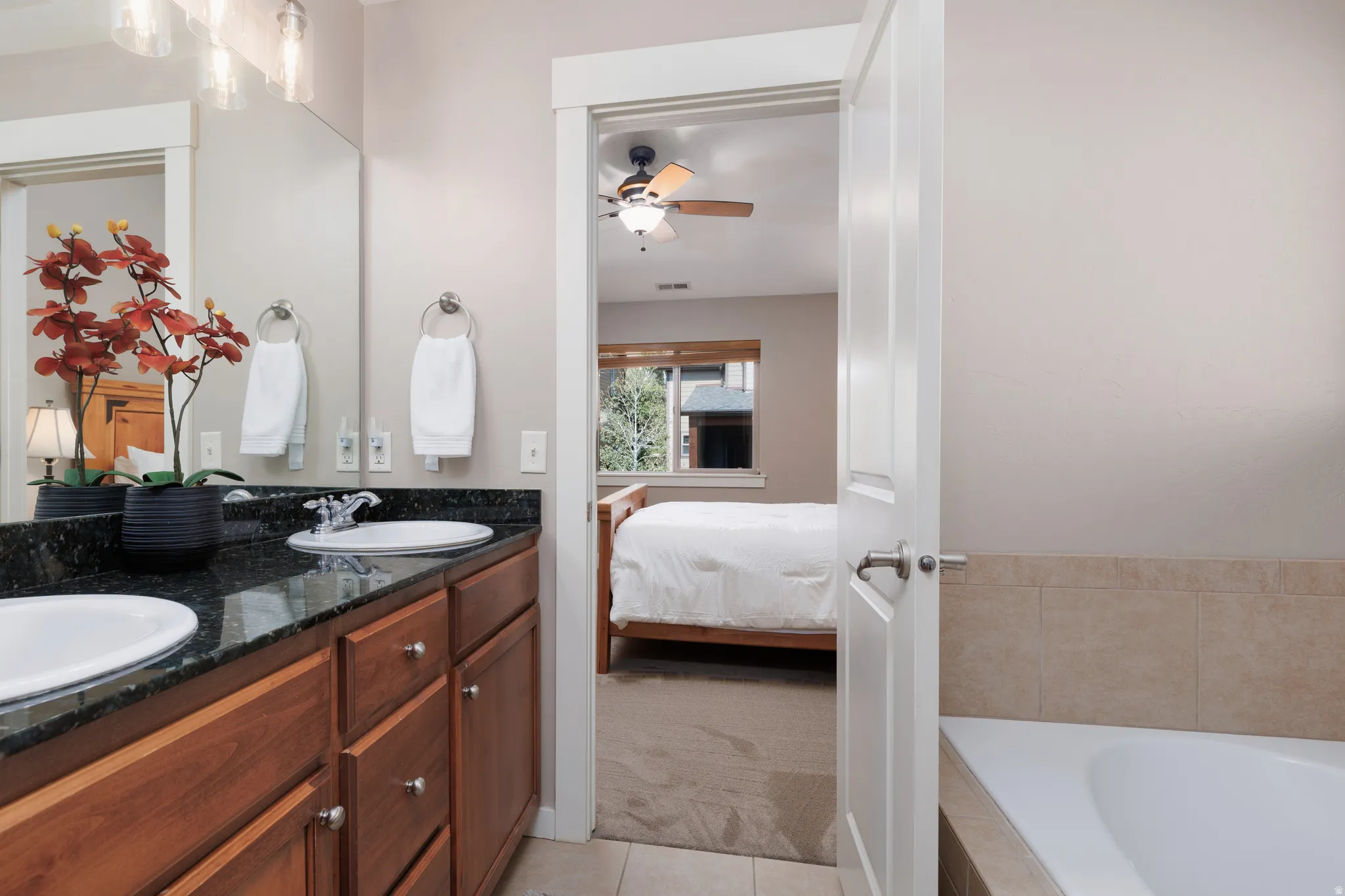 Dual vanity with dark stone countertop, undermount sinks, and wood-finish cabinetry
