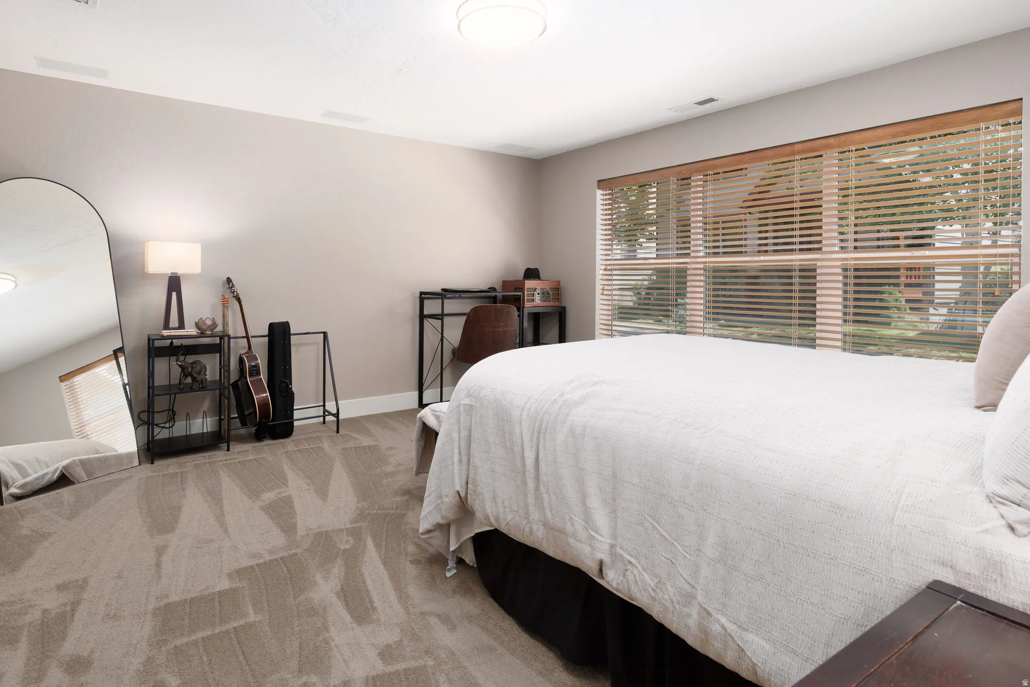 Spacious room featuring patterned carpeting, recessed lighting, and a large window with horizontal blinds