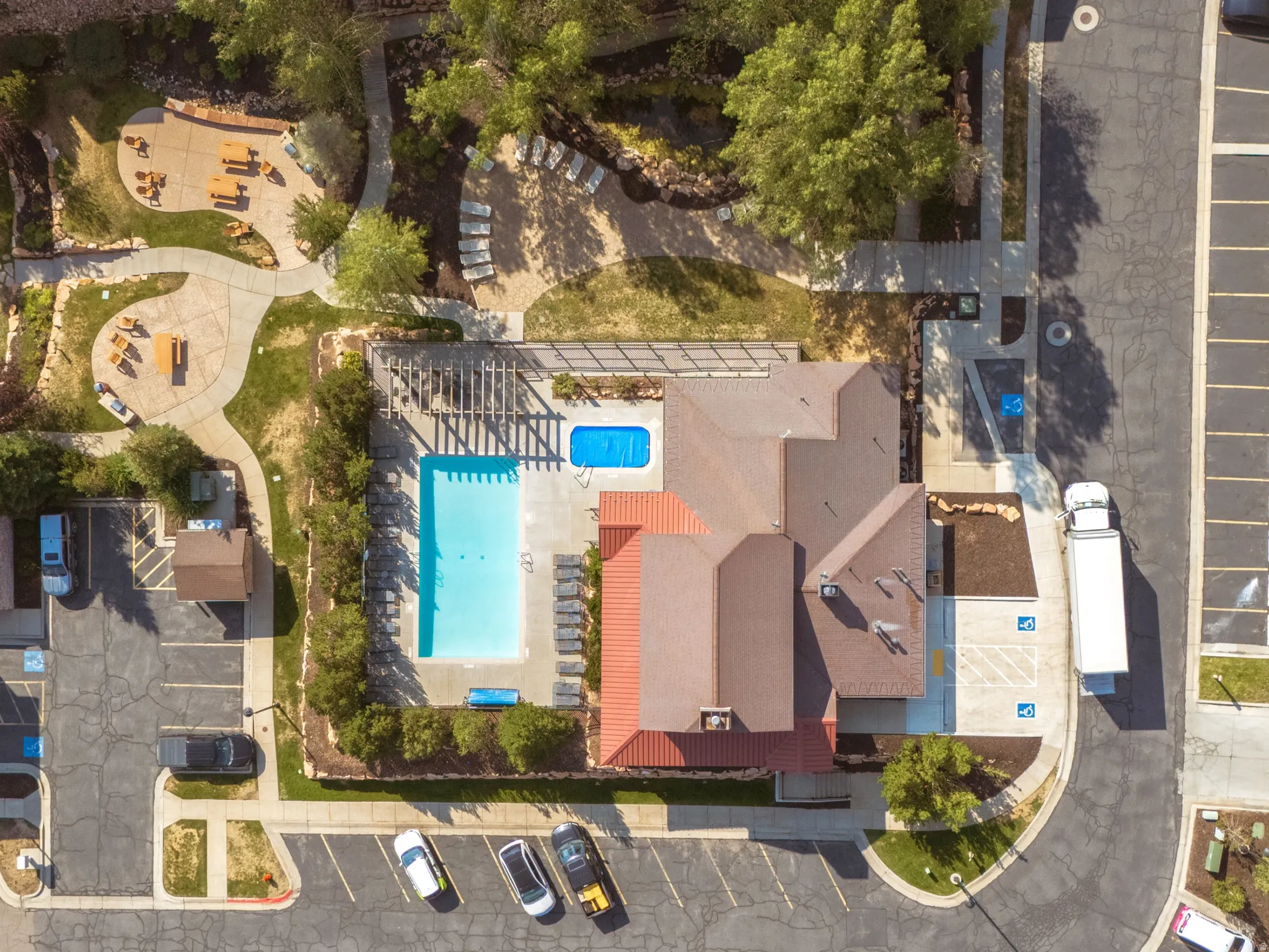 Community building with a large swimming pool, an adjacent smaller pool, and a pergola-covered patio
