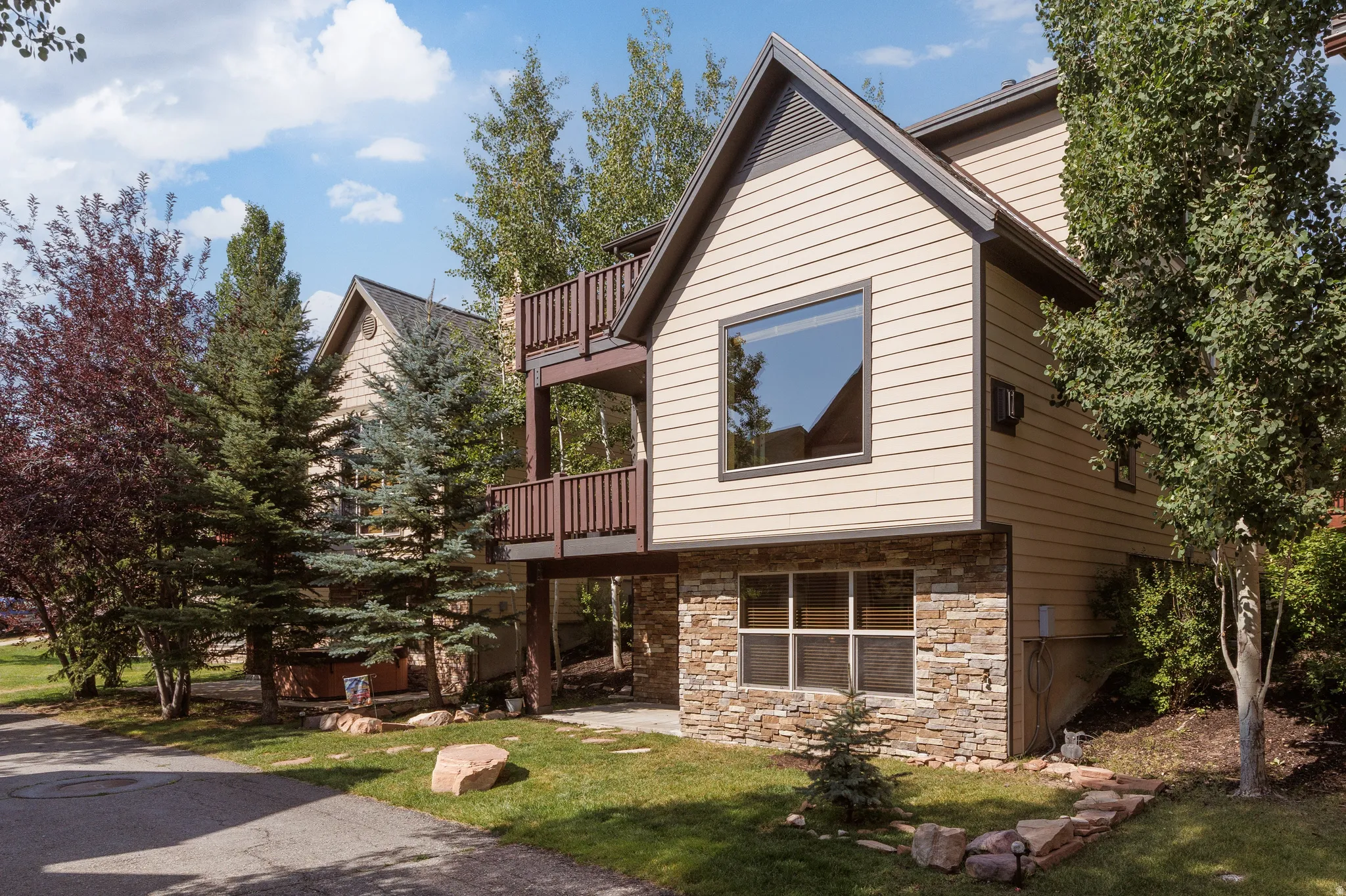 Multi-level residence featuring stacked balconies, stone veneer accents, and peaked gable