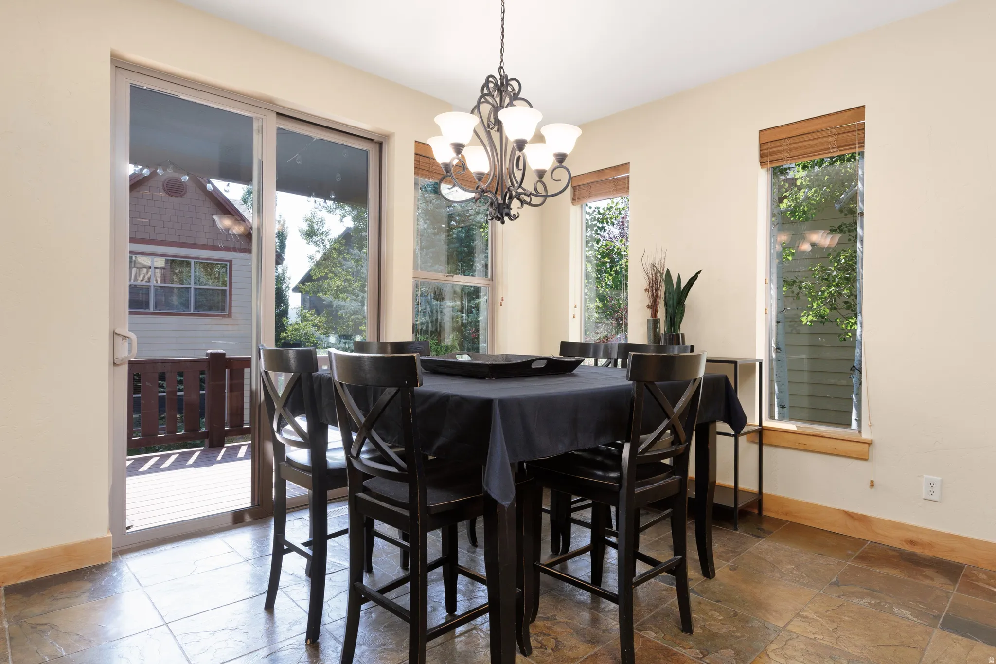 Tiled flooring, sliding glass door, multiple windows, chandelier fixture, and wood trim details
