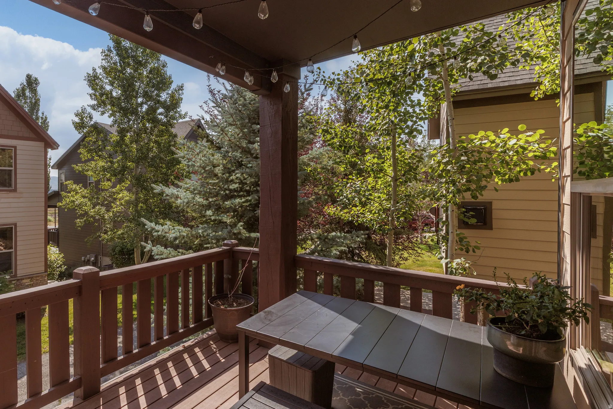 Covered outdoor deck with wood-finish flooring, dark wood railing,