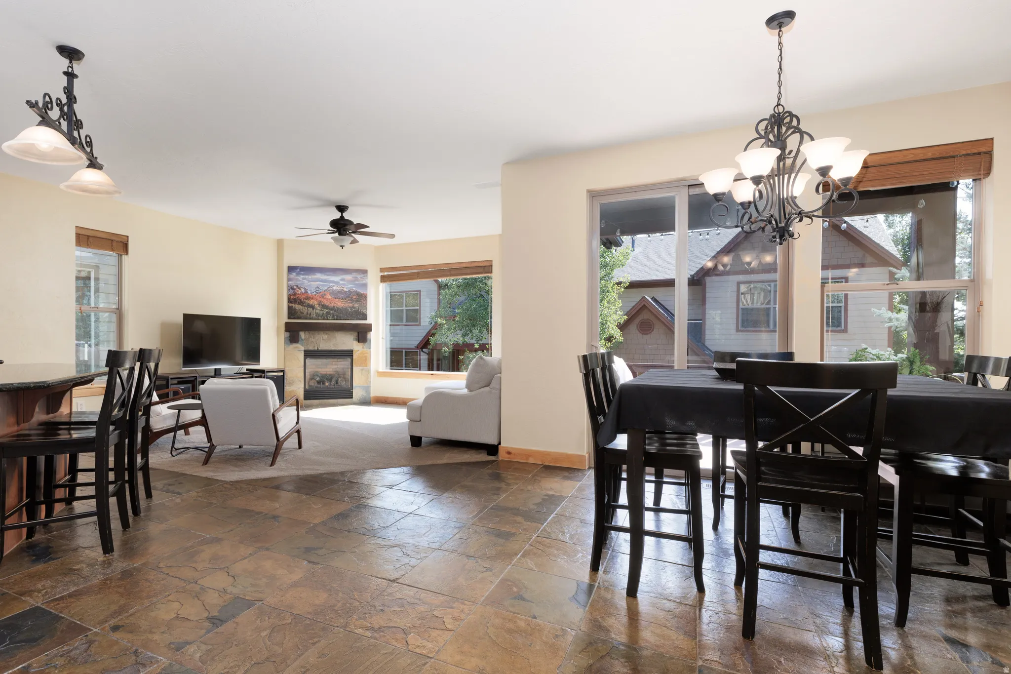 Stone tile flooring, recessed lighting, ceiling fan, fireplace with stone surround, and large windows
