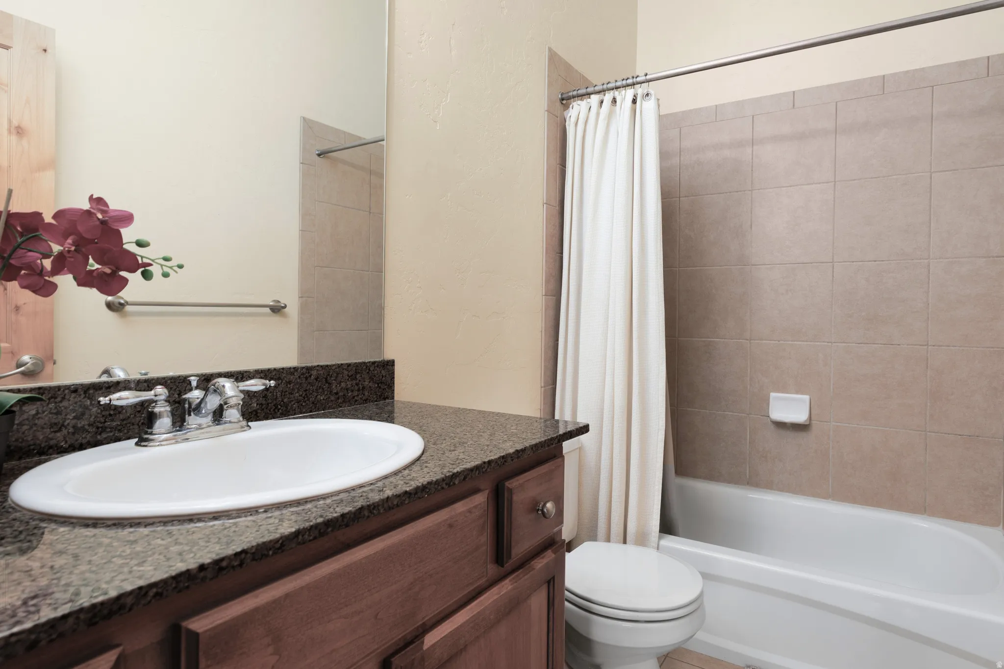 Built-in vanity with a granite-style countertop, undermount sink, and chrome faucet