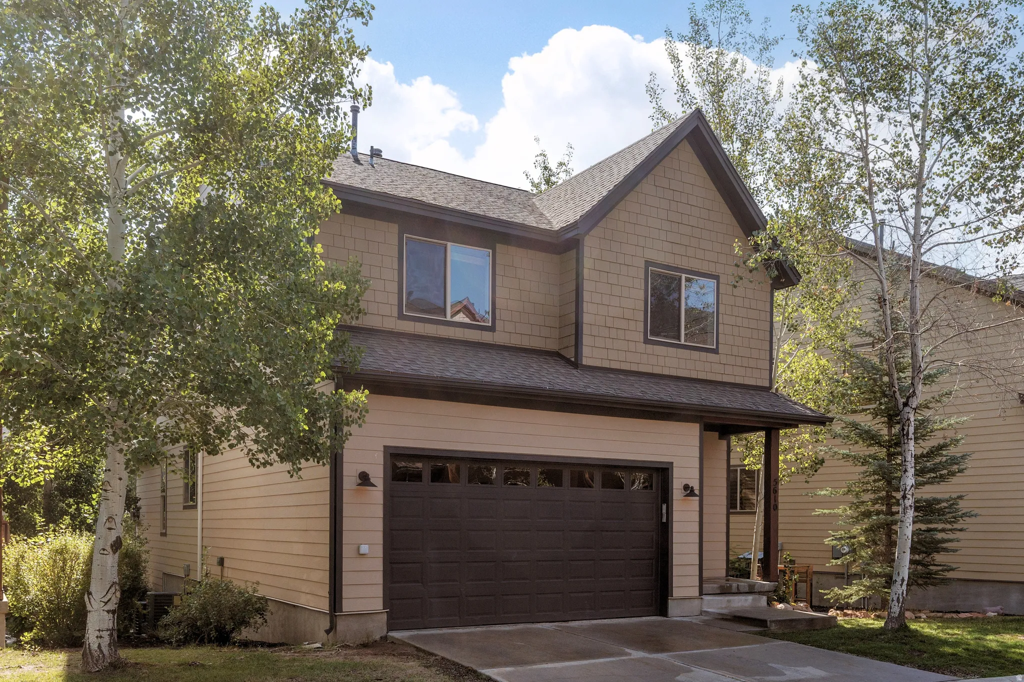 Two-story residence with walk-out basement on .083 acre featuring horizontal siding, shake siding, iron-ore color trim, and  attached two-car garage