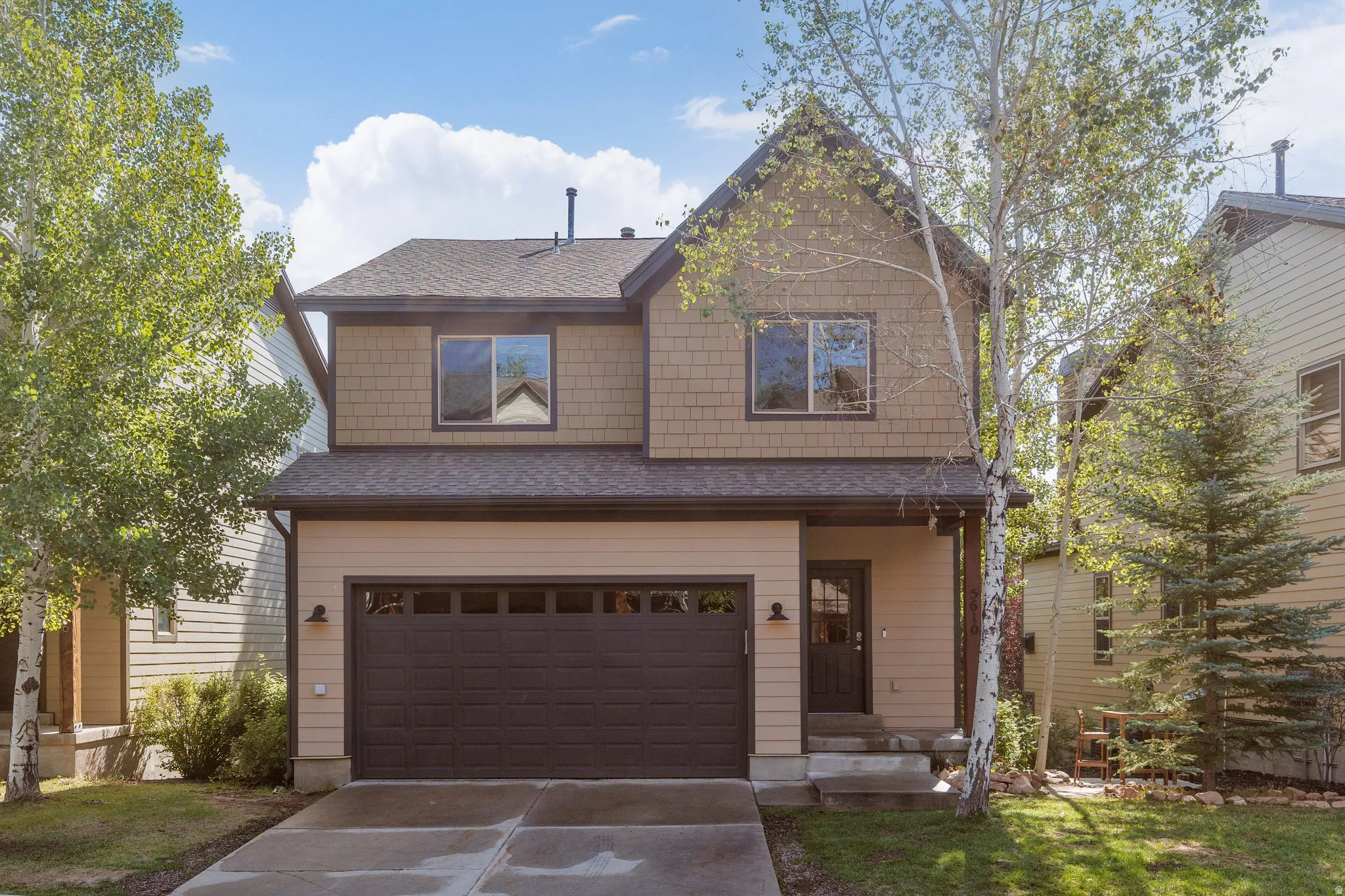 Two-story residence with walk-out basement on .083 acre featuring horizontal siding, shake siding, iron-ore color trim, and  attached two-car garage