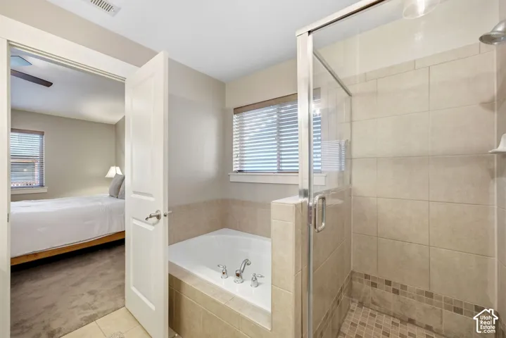 Built-in soaking tub, glass-enclosed shower with tiled surround, and windows with horizontal blinds