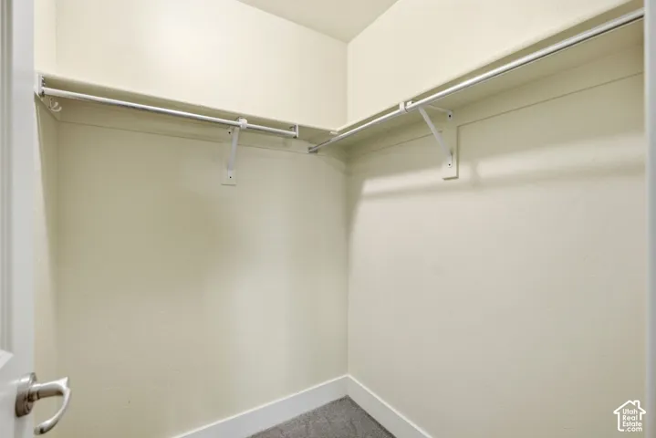 L-shaped closet shelving system with metal hanging rods and light-toned wall finishes