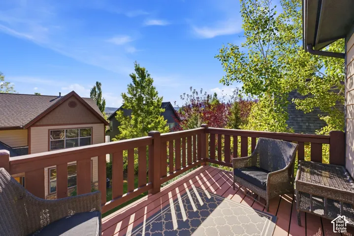 Outdoor deck featuring wood railings, wood-finish flooring, and a perimeter of mature trees