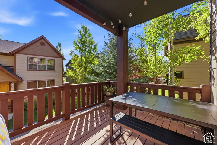 Covered outdoor deck with wood-finish flooring, wood railings, and exposed structural beams