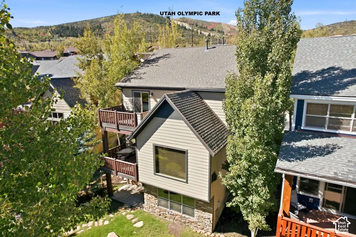 Multi-level residence featuring a gray shingle roof, neutral siding, and a stone-clad foundation