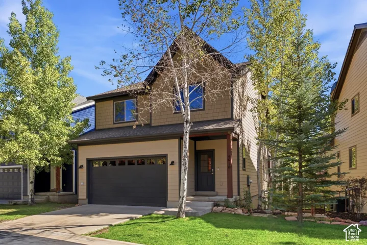 Two-story facade featuring horizontal siding and shake siding accents, an attached two-car garage with a dark panel door, and a covered front entry with a dark-paneled door