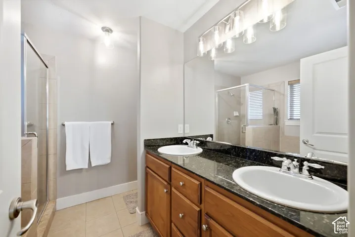 Dual vanity with dark stone countertop, full-width mirror, and track lighting