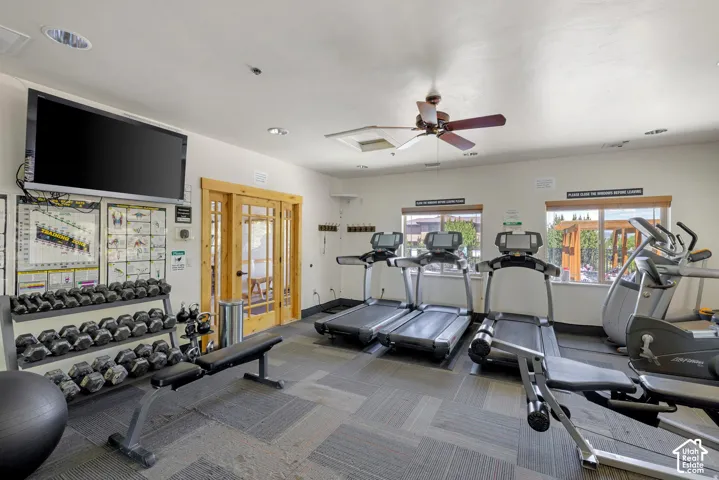 Dedicated fitness space featuring patterned carpet flooring, multiple windows providing natural light, a ceiling fan, and recessed lighting