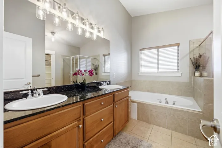 Dual vanity with dark stone countertop, wood-finish cabinetry, and brushed nickel fixtures
