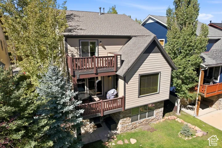 Multi-level property exterior with two balconies, lower patio, and stone foundation