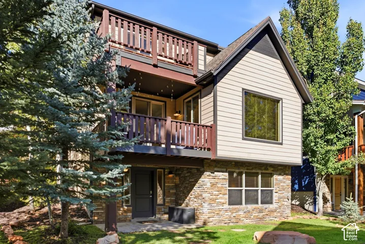 Multi-level exterior featuring stone veneer, horizontal siding, and multiple balconies with dark wood railings