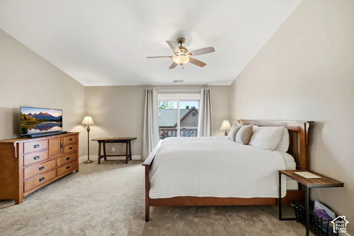 Carpeted flooring, vaulted ceiling, ceiling fan, and sliding glass door to exterior