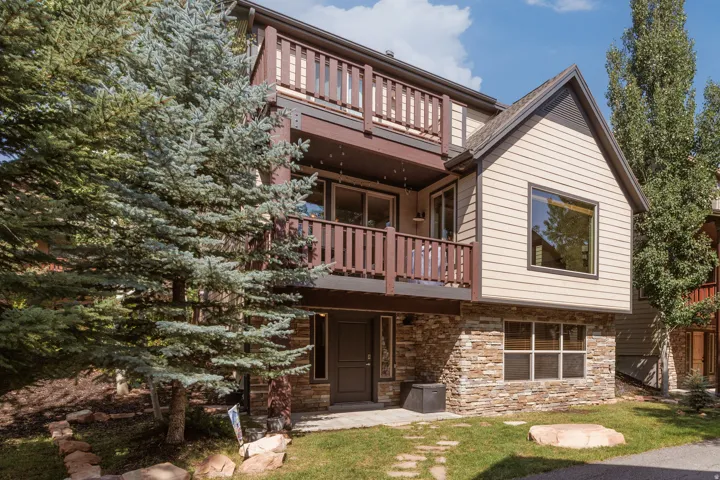 Multi-level residence featuring stacked balconies, stone veneer accents, and peaked gable