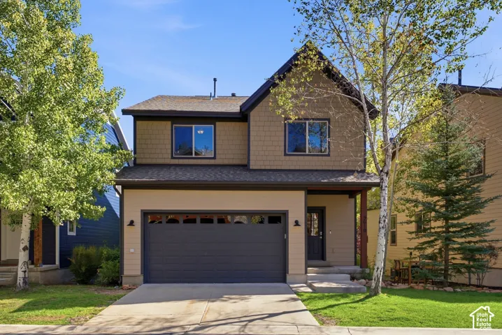 Multi-story exterior with a two-tone facade, attached garage, and paved driveway
