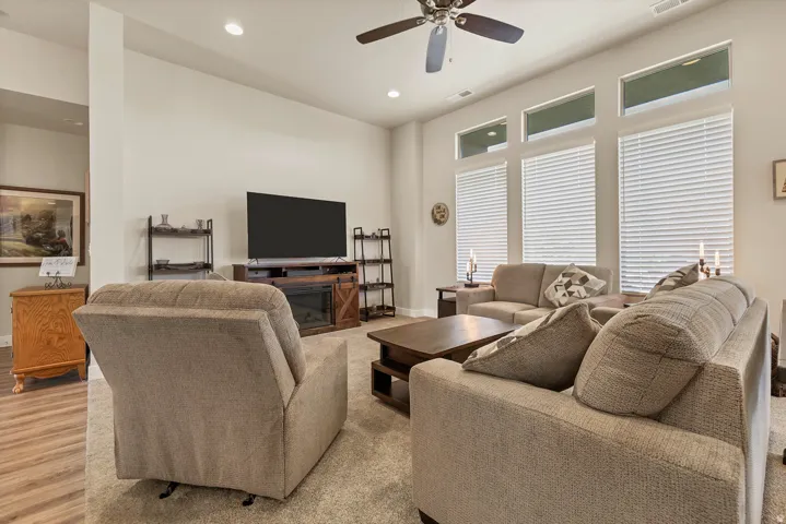 Living space featuring a ceiling fan, recessed lighting, and large windows with blinds