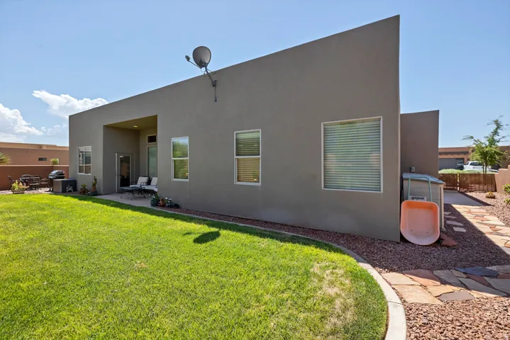 Expansive backyard featuring a manicured lawn, a flagstone pathway, and a covered patio