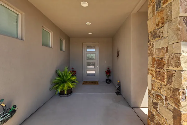 Stucco exterior with stone accents, recessed ceiling lighting, and a modern entry door with frosted glass panels