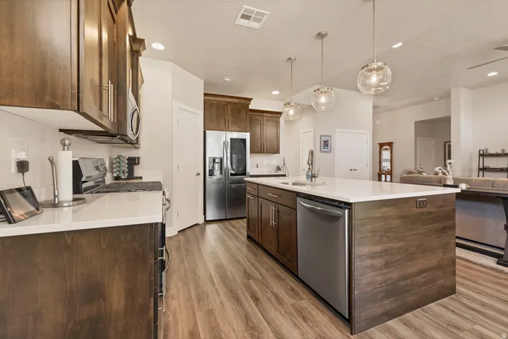 Kitchen featuring wood-finish flooring, stainless steel appliances, white countertops, and abundant cabinetry