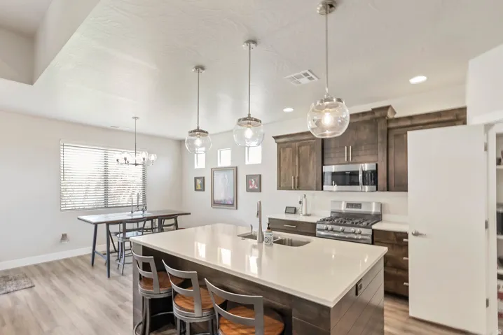 Kitchen island with white countertop, dark wood-finish cabinetry, stainless steel appliances, and wood-finish flooring