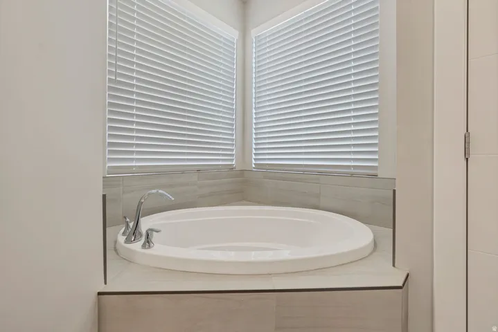 Built-in soaking tub with a polished chrome faucet, surrounded by light-toned tile