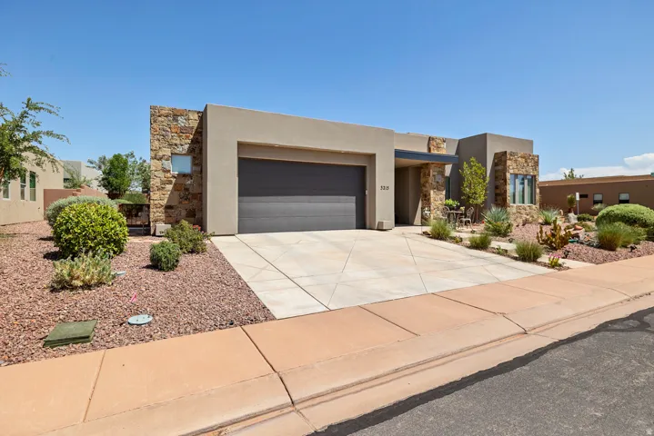 Contemporary stucco exterior with stone accents, a concrete driveway, and a dark garage door