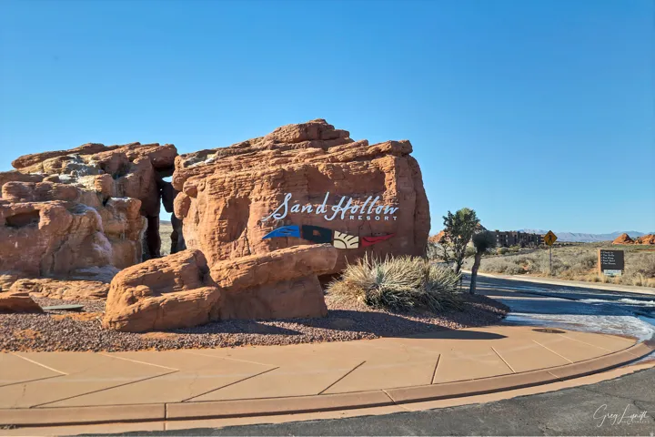 Red rock formations with integrated signage, desert landscaping, and paved driveway