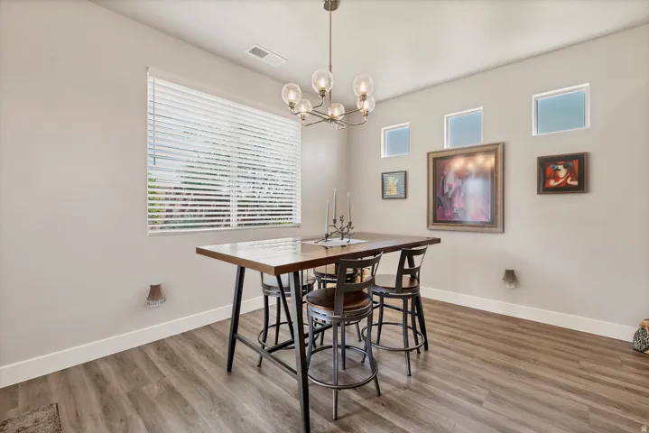 Wood-finish flooring, recessed windows, wall-mounted light fixtures, and a multi-bulb chandelier