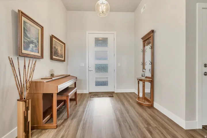 Entryway featuring wood-finish flooring, a contemporary overhead light fixture, and a white front door with four frosted glass panels