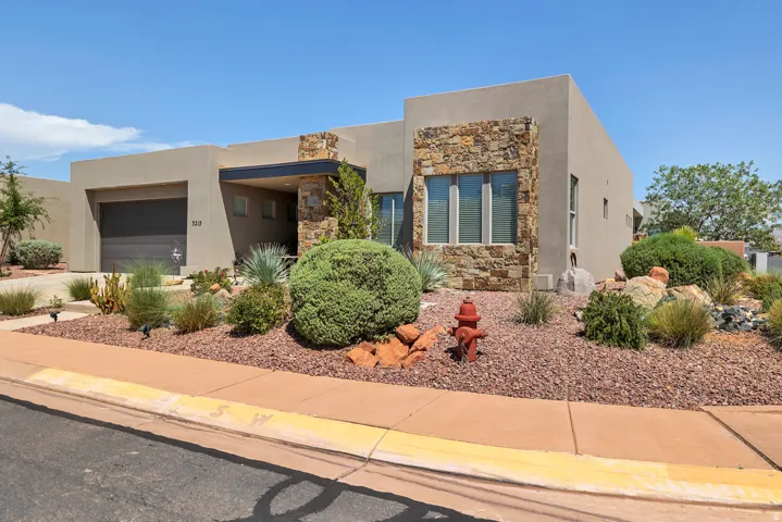 Contemporary stucco exterior with stone accents, integrated garage, covered entry, and low-maintenance landscaping