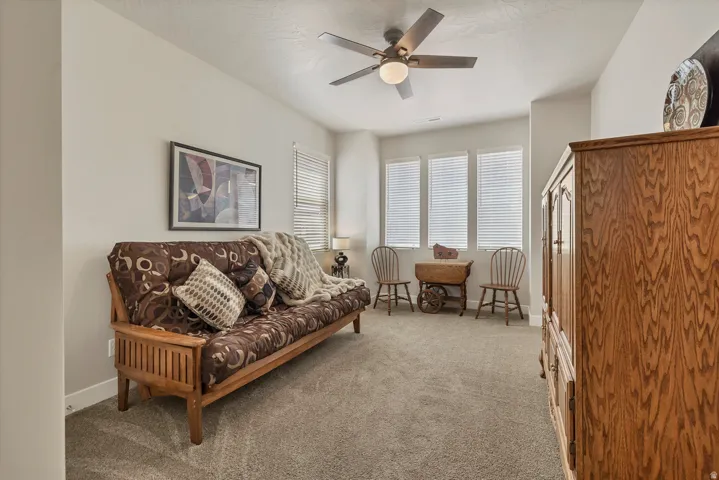 Carpeted room featuring multiple windows with blinds and a ceiling fan with integrated lighting