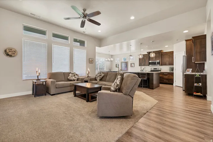 Open-concept living space featuring high ceilings, a ceiling fan, and large windows with blinds