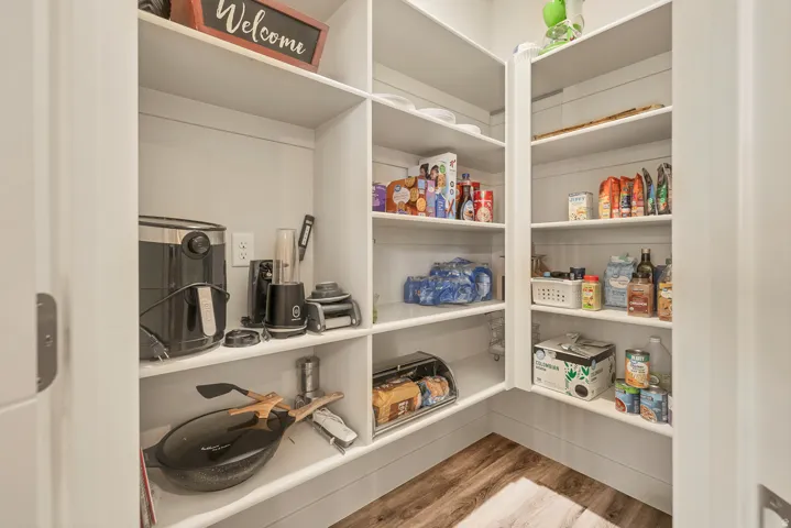 Built-in pantry shelving with white finishes and wood-finish flooring