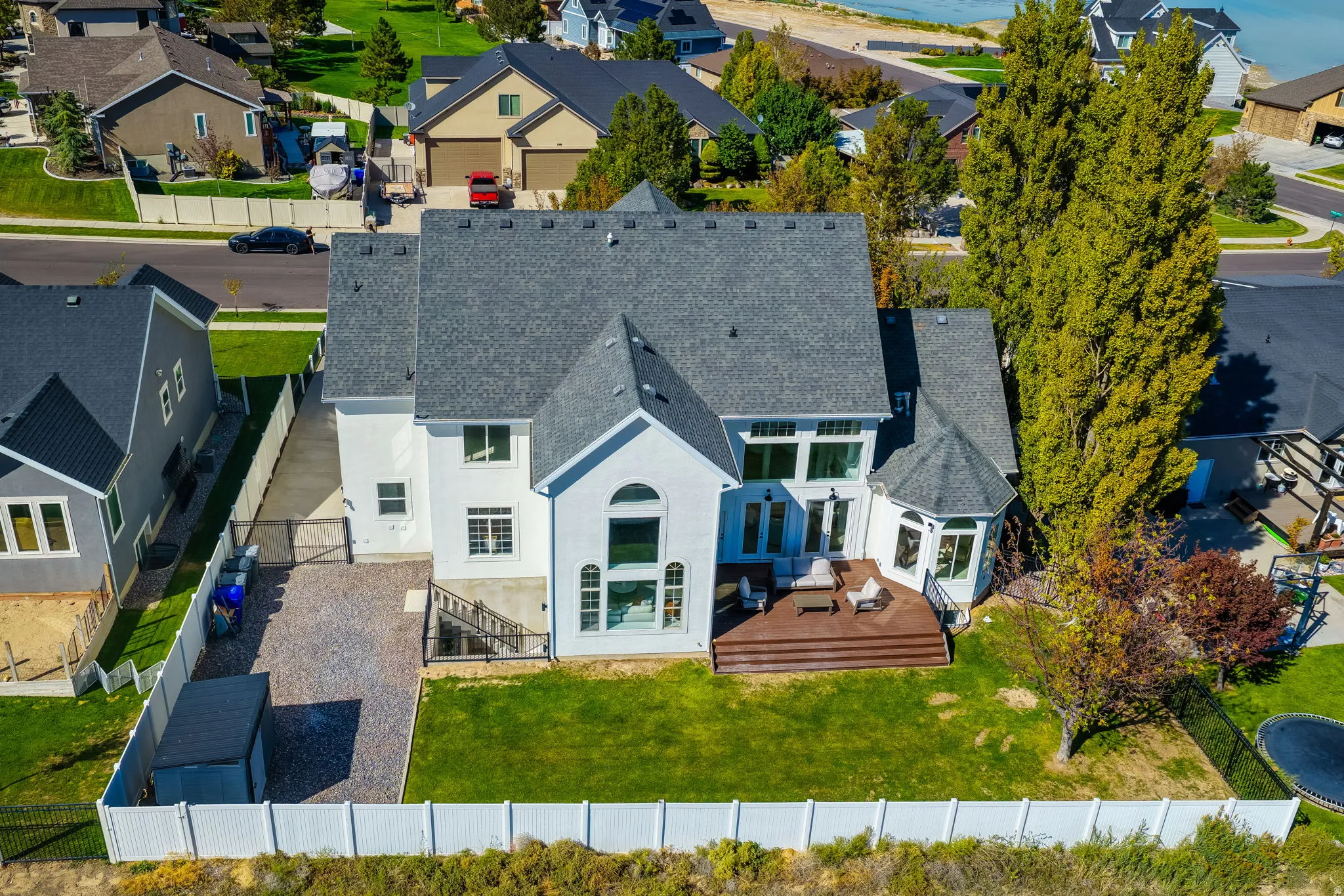 White stucco exterior with a multi-gabled roof, large arched window, and a rear wood-finish deck