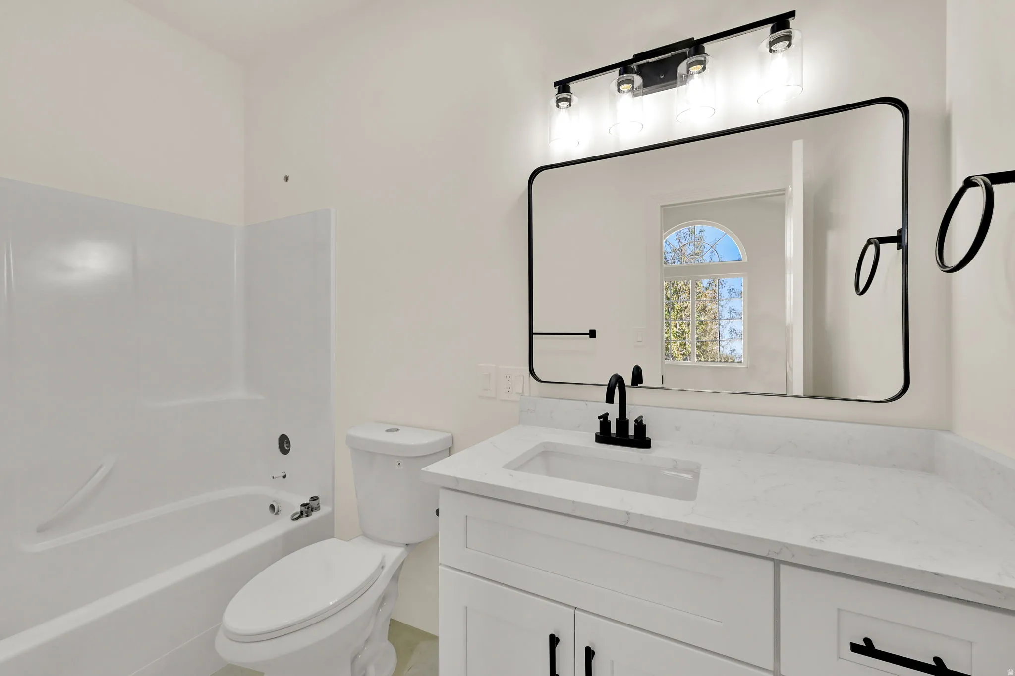 White vanity with black hardware, rectangular undermount sink, and light-toned countertop
