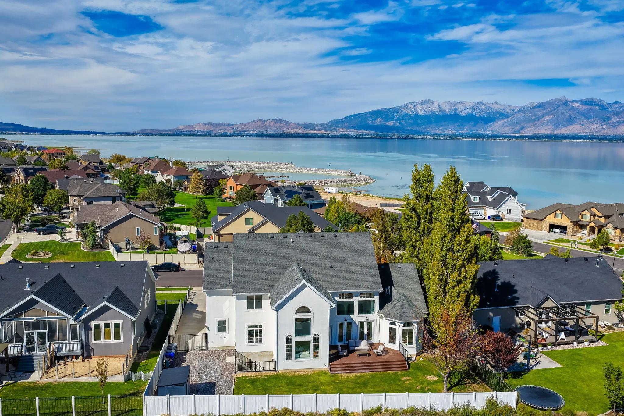 Lakefront property featuring a two-story residence with an expansive backyard, large deck, and mature trees