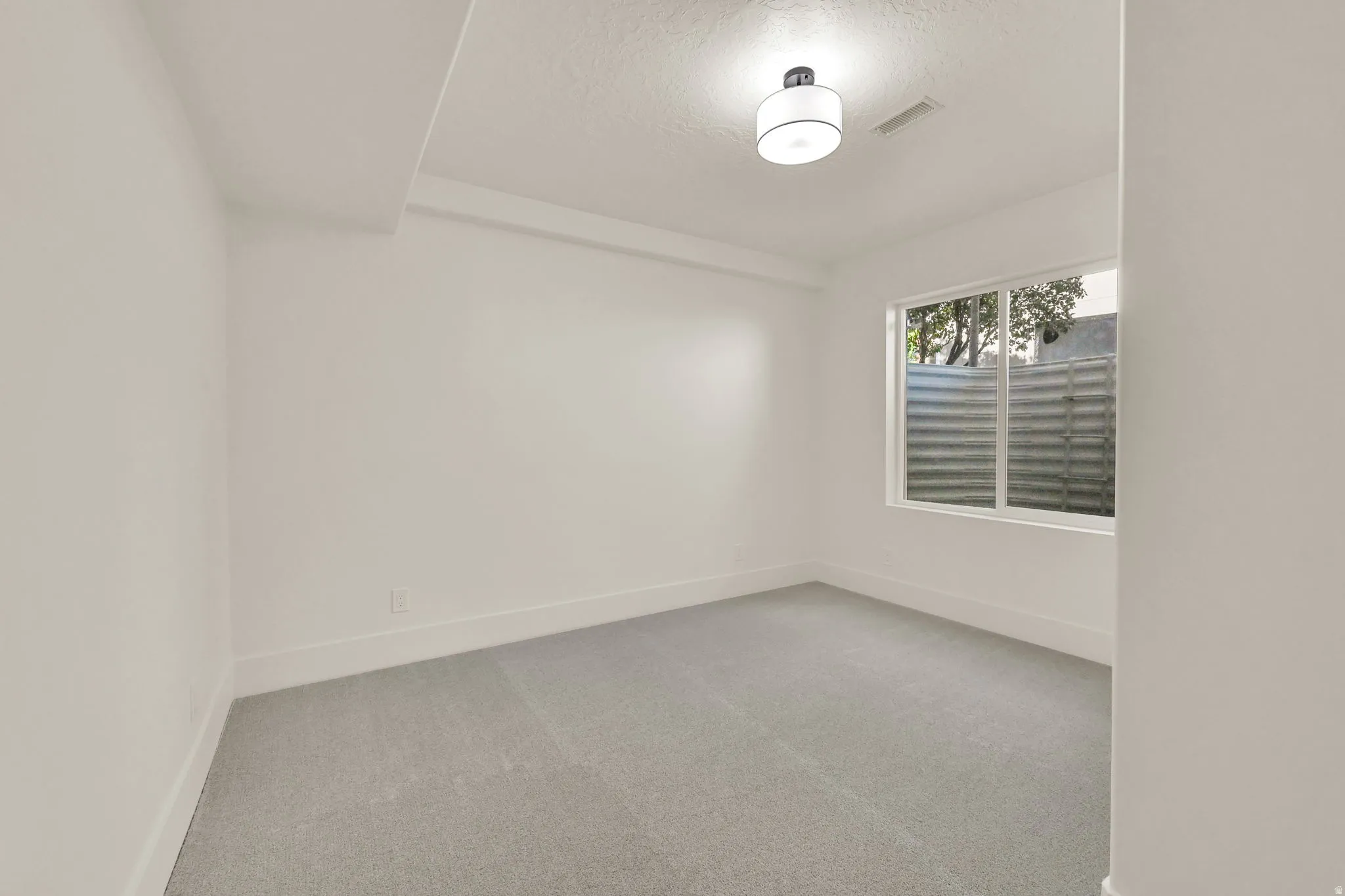 Recessed window with white trim, light gray wall-to-wall carpeting, and a flush-mount ceiling light