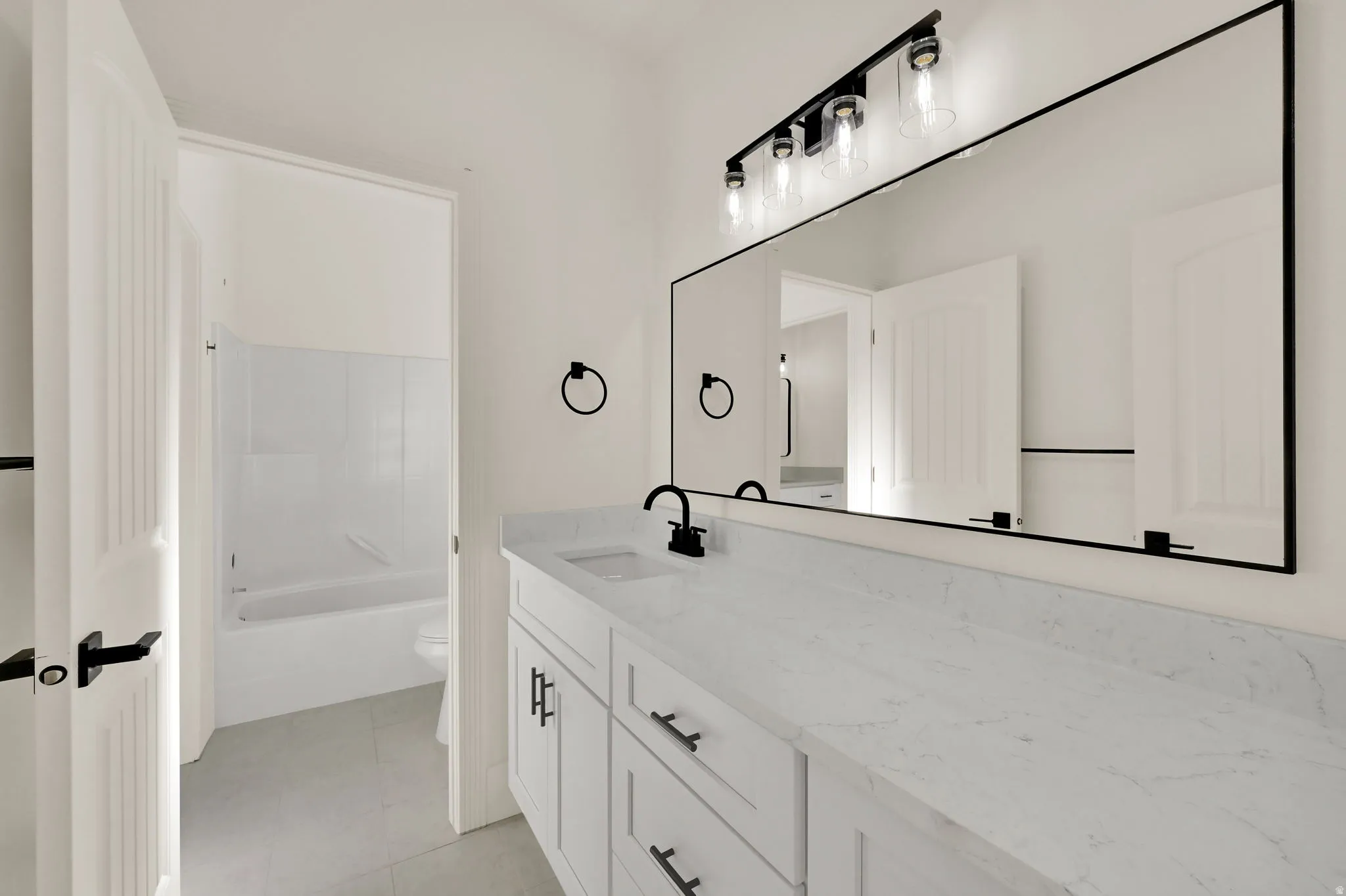 Double vanity with white cabinetry and integrated sinks, complemented by matte black hardware and a full-width mirror
