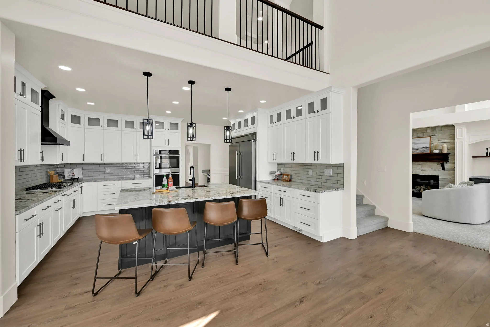 Gourmet kitchen with white cabinetry, built-in appliances, a large center island, and wood-finish flooring