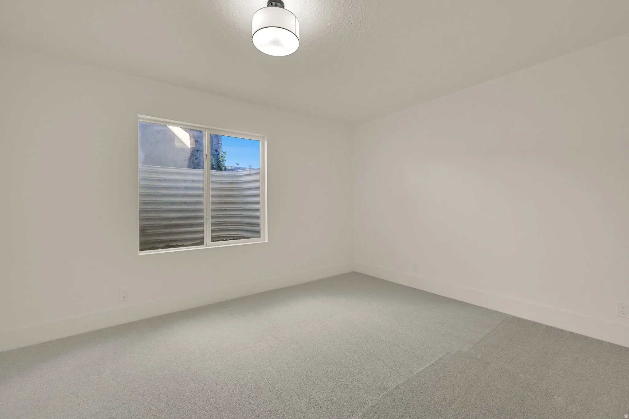 Recessed window with a metal window well, light gray carpet flooring, and a flush-mount ceiling light fixture
