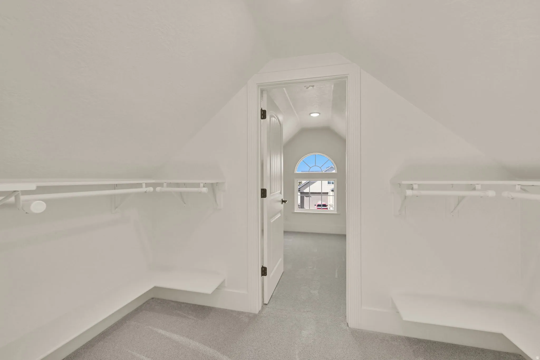 Built-in shelving with hanging rods in closet leading to a secret room with a window!