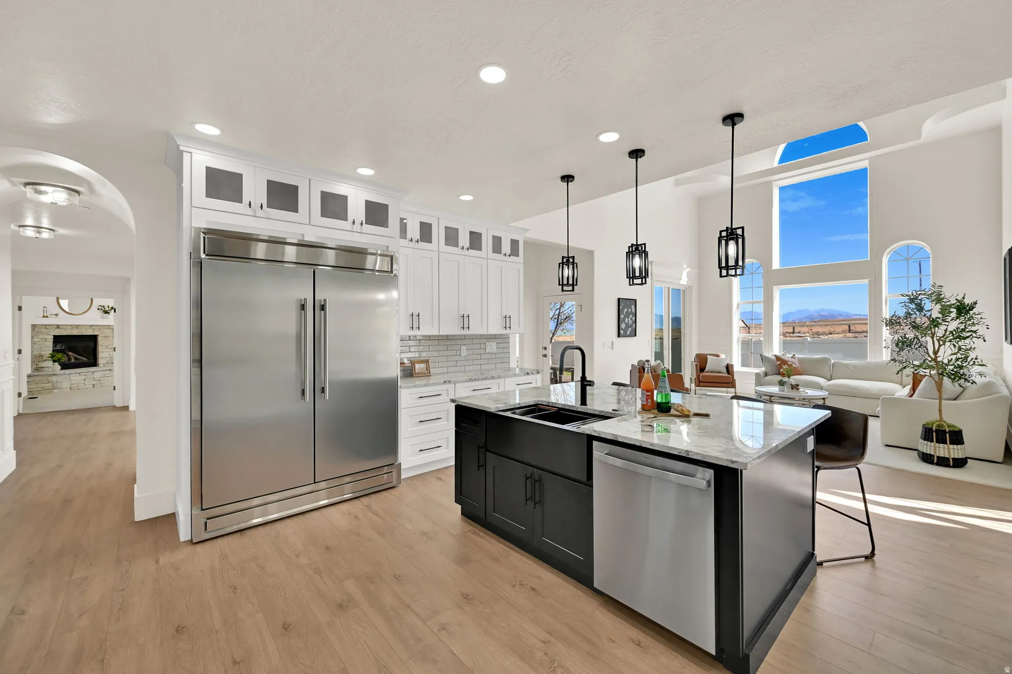Gourmet kitchen with stainless steel appliances, a large island with sink, pendant lighting, and wood-finish flooring