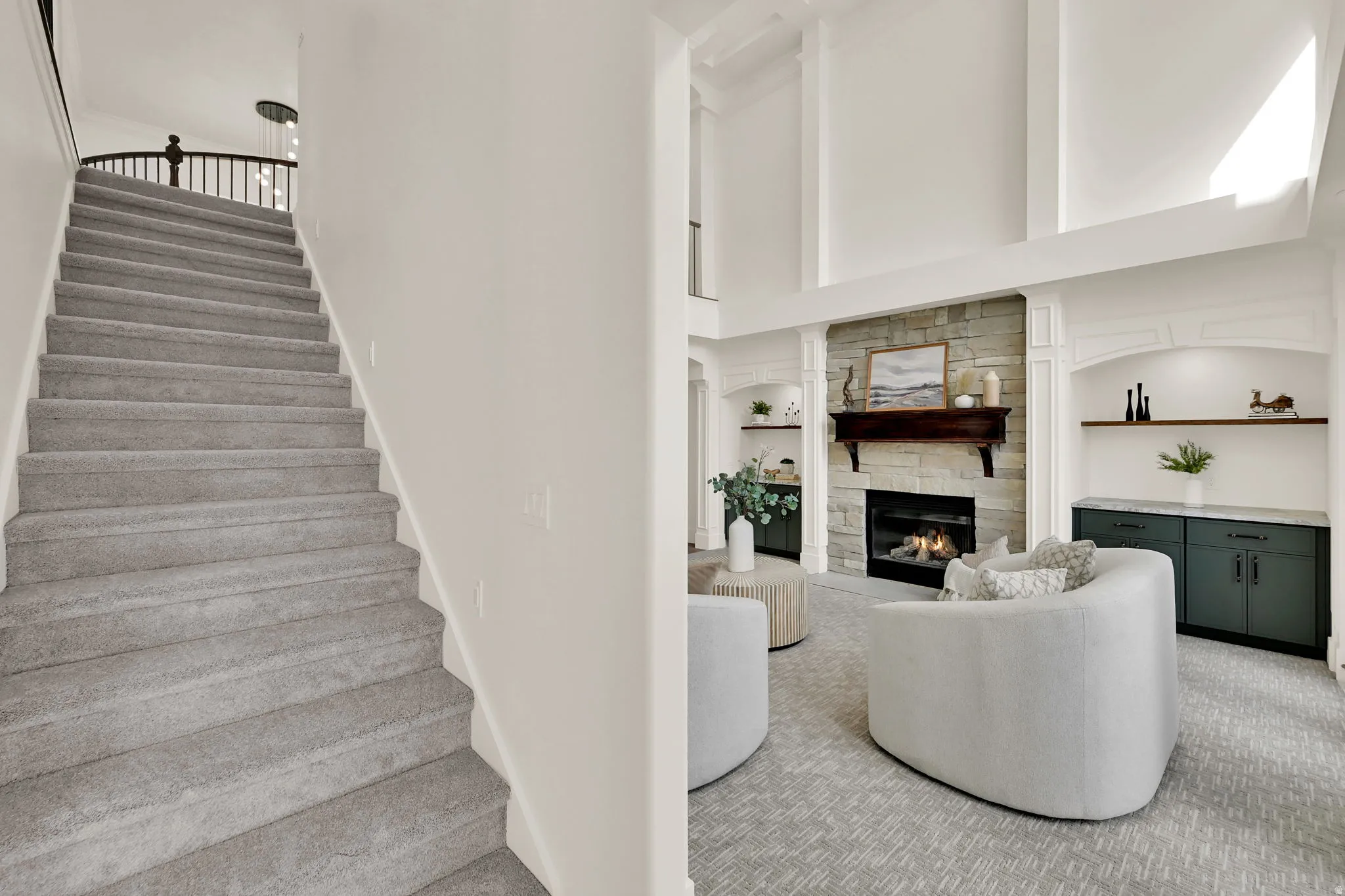 Two-story living area with a stone-clad fireplace and wood mantel, complemented by built-in cabinetry and shelving