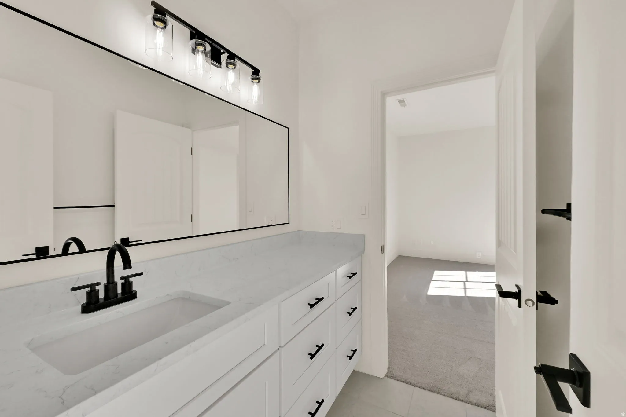 Double vanity with integrated sink, white cabinetry, and matte black hardware