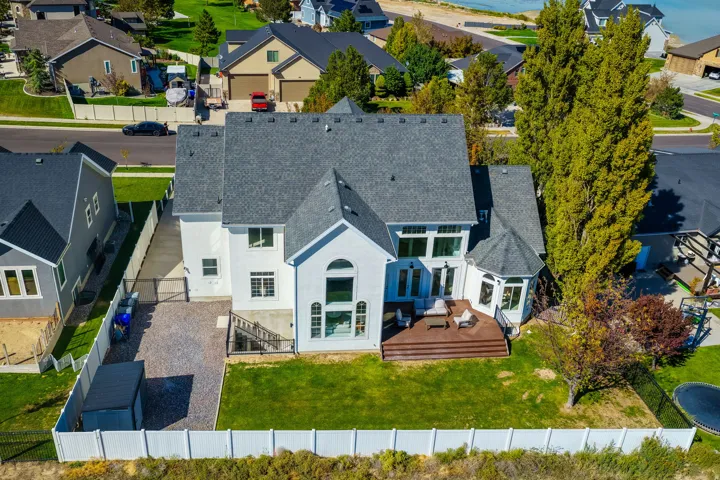 White stucco exterior with a multi-gabled roof, large arched window, and a rear wood-finish deck